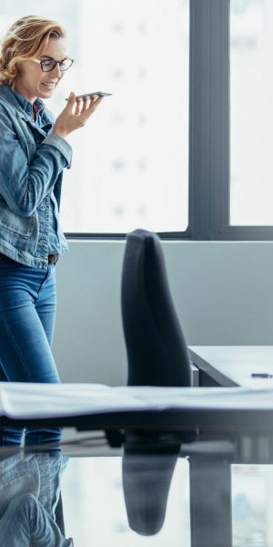 Horizontal shot of businesswoman using mobile phone in office. Female architect talking on speaker phone.